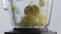 Dropping pieces fruits blender with spinning blades close up. Vitamin nutrition