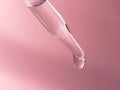 A dropping pipet, pipette, medicine dropper, dropping with transparent liquid or fluid, on pink background. Royalty Free Stock Photo