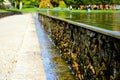 Dropping pool water on rough natural stone wall in public park. Royalty Free Stock Photo