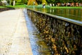 Dropping pool water on rough natural stone wall in public park. Royalty Free Stock Photo