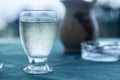 Drops of condensation on the misted glass of a glass with a transparent liquid on the table with a blue tablecloth and a blurred b Royalty Free Stock Photo