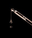 Drops dripping down from cosmetic pipette closeup on a black background Royalty Free Stock Photo