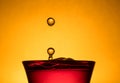 Drops of Golden Beverage Into a Crimson Red Glass Royalty Free Stock Photo