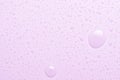 Drops of micellar water or cosmetic tonic on a pink background. Close-up, macro photography