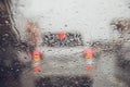 Drops Of Rain Drizzle on the glass windshield in the evening. street in the heavy rain. Bokeh Tail light and Traffic lights in cit Royalty Free Stock Photo