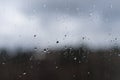 The drops of rain flow down on the dusty glass. Background is blurred Royalty Free Stock Photo
