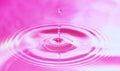 Drops of water fall into the water, forming perfect concentric circles. Abstract pink background Royalty Free Stock Photo