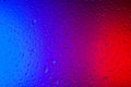 Drops of water on glass in red-blue neon light. Rain on the glass against the background of two colored lights. Royalty Free Stock Photo