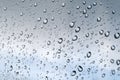 Drops of water on the glass window against a blurred blue and gray sky background on a rainy autumn day. Selective focus Royalty Free Stock Photo