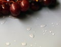 Drops of Water and Some Purple Grapes on a Light Blue Surface Royalty Free Stock Photo
