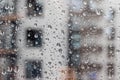 Drops of water on the window glass against a blurred background of a house on a rainy cloudy day. Drops of different sizes Royalty Free Stock Photo