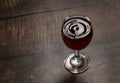 Drops of wine and waves forming in a glass full of red wine standing on a wooden table Royalty Free Stock Photo