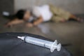 Drug addict and syringe on floor