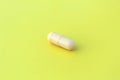 The drug in a beige capsule lies alone on an isolated yellow background. Royalty Free Stock Photo