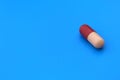 The drug in a two-color capsule lies alone on an isolated blue background. Royalty Free Stock Photo