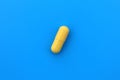 The drug in a yellow capsule lies alone on an isolated blue background. Royalty Free Stock Photo