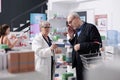 Drugstore employee helping customer with pharmaceutical treatment explaining cardiology pills leaflet