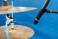 Drum cymbals and microphone are located on a blue background. Amplification and recording of the sound of musical instruments.