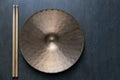 Drum stick and crash cymbal on black table background, top view