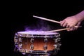 Drum sticks hitting snare drum with splashing water on black background under studio lighting Royalty Free Stock Photo