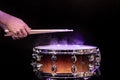 Drum sticks hitting snare drum with splashing water on black background under studio lighting