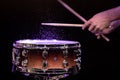 Drum sticks hitting snare drum with splashing water on black background under studio lighting Royalty Free Stock Photo