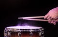 Drum sticks hitting snare drum with splashing water on black background under studio lighting. Close up Royalty Free Stock Photo