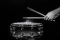 Drum sticks hitting snare drum with splashing water on black background under studio lighting. Black and white. Close up Royalty Free Stock Photo