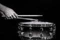 Drum sticks hitting snare drum with splashing water on black background under studio lighting. Black and white. Close up Royalty Free Stock Photo