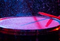 Drum sticks hitting snare drum with splashing water on dark background with red and blue studio lighting. Dynamic scene Royalty Free Stock Photo