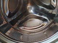 The drum of the washing machine from the inside. Shiny metal tank with holes and bulges. Stainless steel surface with holes, made