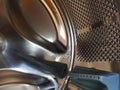 The drum of the washing machine from the inside. Shiny metal tank with holes and bulges. Stainless steel surface with holes, made