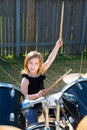 Drummer blond kid girl playing drums in tha backyard Royalty Free Stock Photo