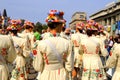 Drummer girls in beautiful white costumes and fashionable hats with bright flowers stand at the city festival, carnival