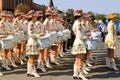 Drummer girls in beautiful white costumes and fashionable hats with bright flowers stand at the city festival, carnival. Ukrainian