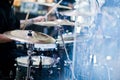 Drummer play at drum set on stage in a concert hall behing glass wall