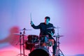 Young man drummer playing on drums on music concert. Club lights, artist show Royalty Free Stock Photo