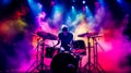 drummer plays drums on stage at concert in beams of color lights