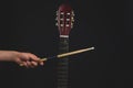 Drumstick in the hand and guitar fretboard close up. acoustic musical instrument