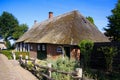 View on typical dutch farm house with reed roof, red brick wall, green doors and wood fence