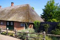 View on typical dutch farm house with reed roof, red brick wall, green doors and wood fence