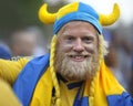 Drunk bearded soccer Swedish fan, face painted in yellow blue national colors, supporting his football team on the street