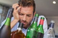 Drunk businessman slumped beside many spirit bottles