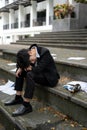 A drunk, hopeless Asian businessman sits on the stairs in front of the building after getting fired