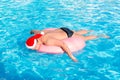 A drunk guy in santa claus hat swims on inflatable circle in the pool. travel of a Russian tourist