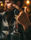 Drunk and hangover driver with car key in alcoholism problem and alcohol abuse concept. Man with beard holds glass of