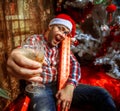 Drunk hipster with glass of champagne under Christmas tree