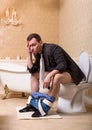 Drunk man with pants down sitting on toilet bowl