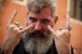 Drunk man in the street during free event making rock gesture with skull rings on the hands