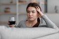 Drunk unhappy caucasian young woman with glass of wine suffering from depression and headache and relax at home Royalty Free Stock Photo